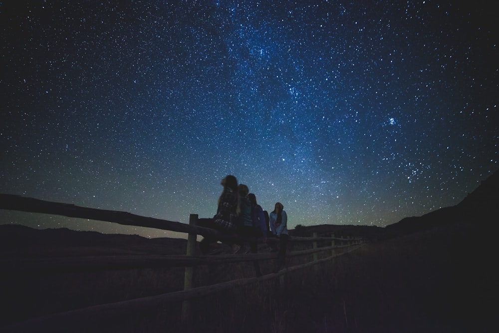 Diverse donne sedute sulla recinzione che guardano la Via Lattea