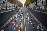A group of runners jogging together along a tree-lined city street with colorful buildings.