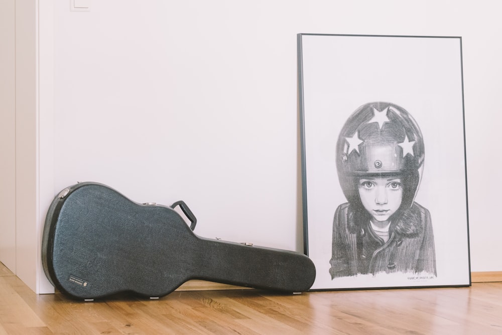 black guitar case beside white wall