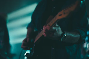 A moody close-up of a musician passionately playing guitar under soft spotlight.