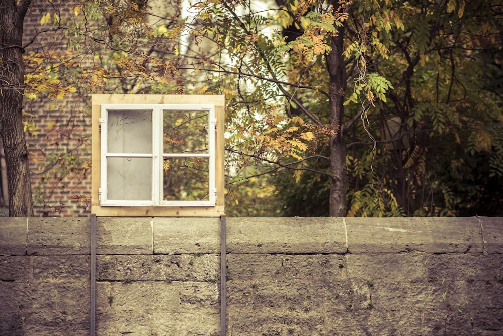 white and brown 4-pane window on gray concrete fence