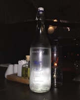 Crystal-clear Asva alkaline water bottles arranged on a sleek, reflective surface with soft blue and green lighting.