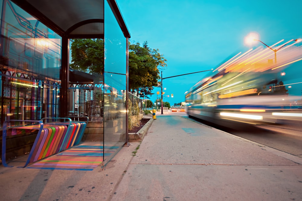 Zeitrafferfotografie eines vorbeifahrenden Busses an einer Glaswand während des Tages