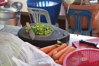 A warm kitchen scene with freshly chopped vegetables beside a pd life wooden chopping board in use.