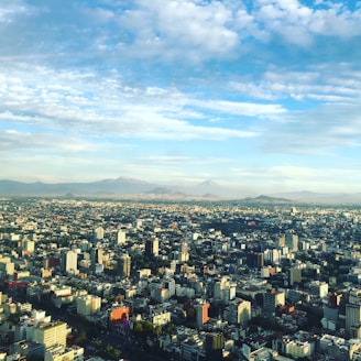 aerial photo of concrete buildings under white clouds at daytime