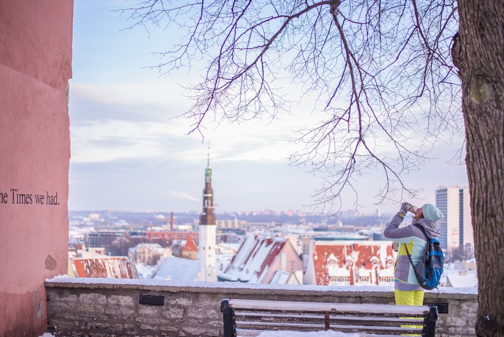 woman drinking near bench under tree