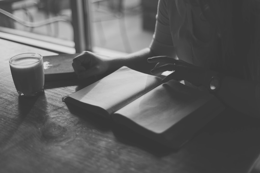 Photo en niveaux de gris d’une personne lisant un livre