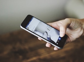 Close-up of hands managing a smartphone with social media apps open.