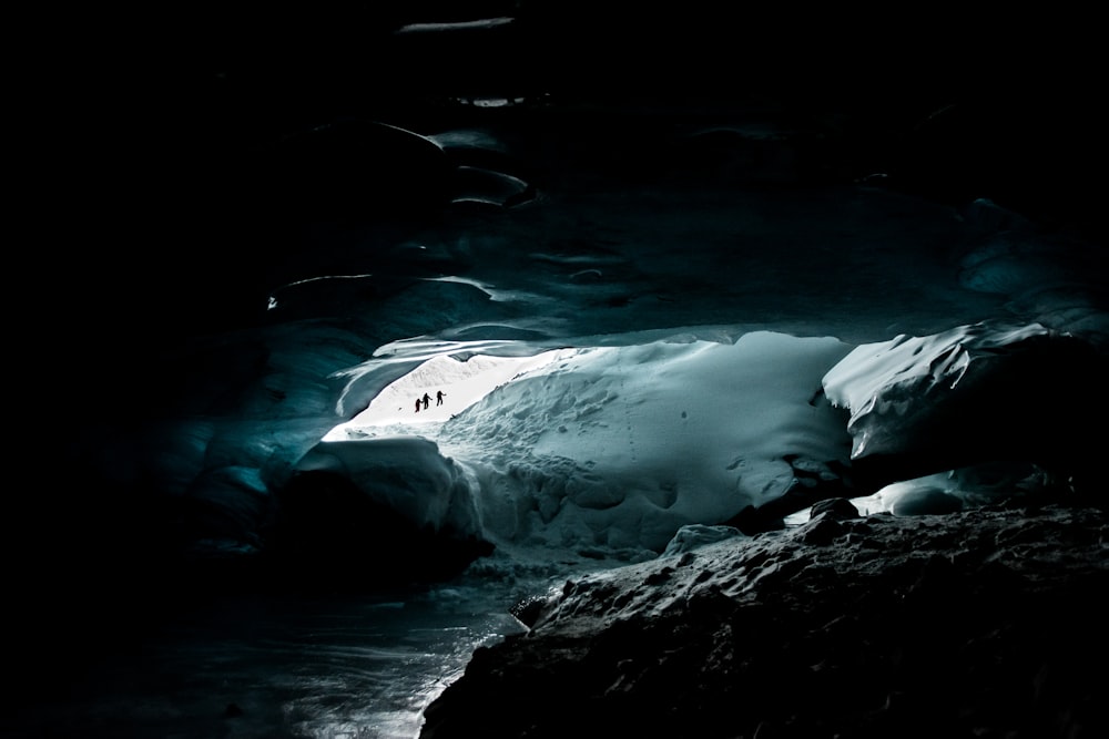 People in the opening of a cave filled with ice and snow