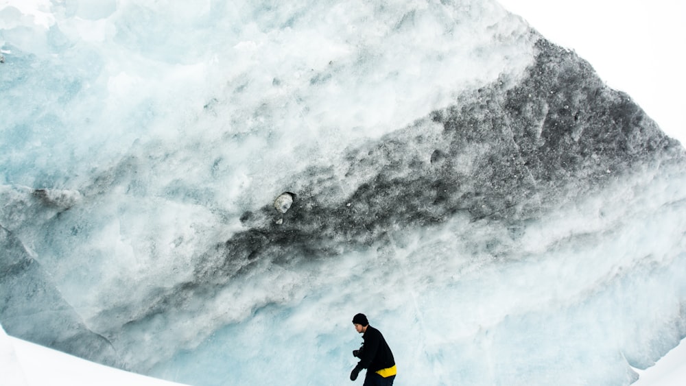 man wearing black jacket and black beanie cap on icy mountain