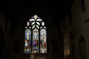 Group photo of church elders standing in front of a stained glass window with wine red accents
