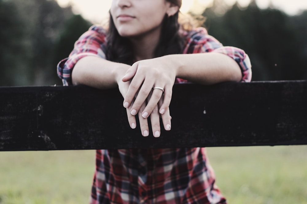 Woman wearing flannel stands over wooden post with dark lighting