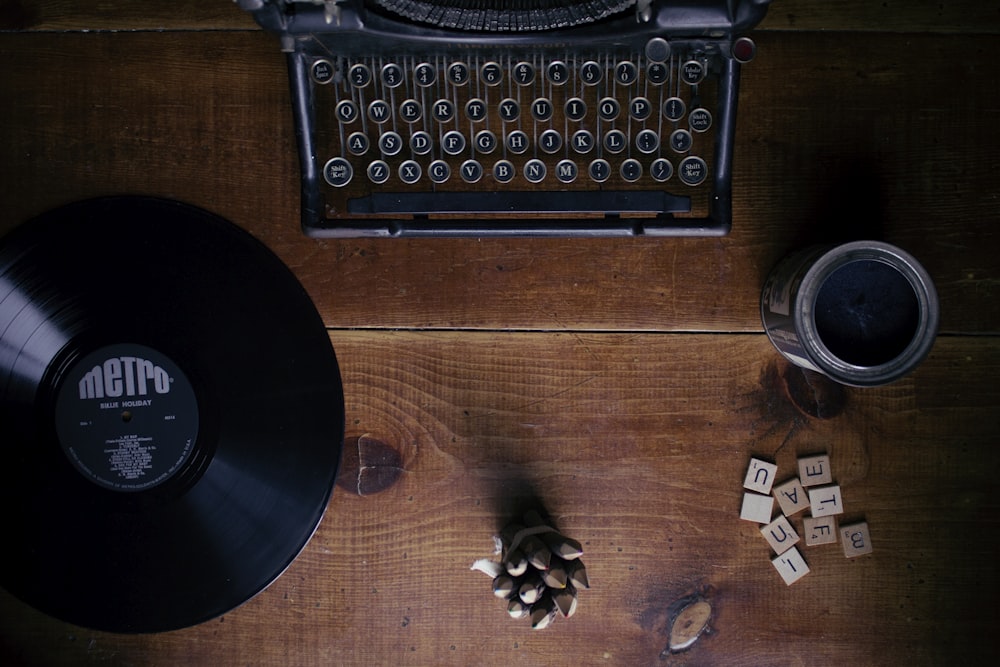 máquina de escribir negra junto a un disco de vinilo negro de Metro