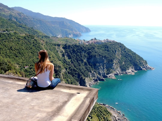 woman sitting on the edge of concrete block facing coast in Parco Nazionale delle Cinque Terre Italy