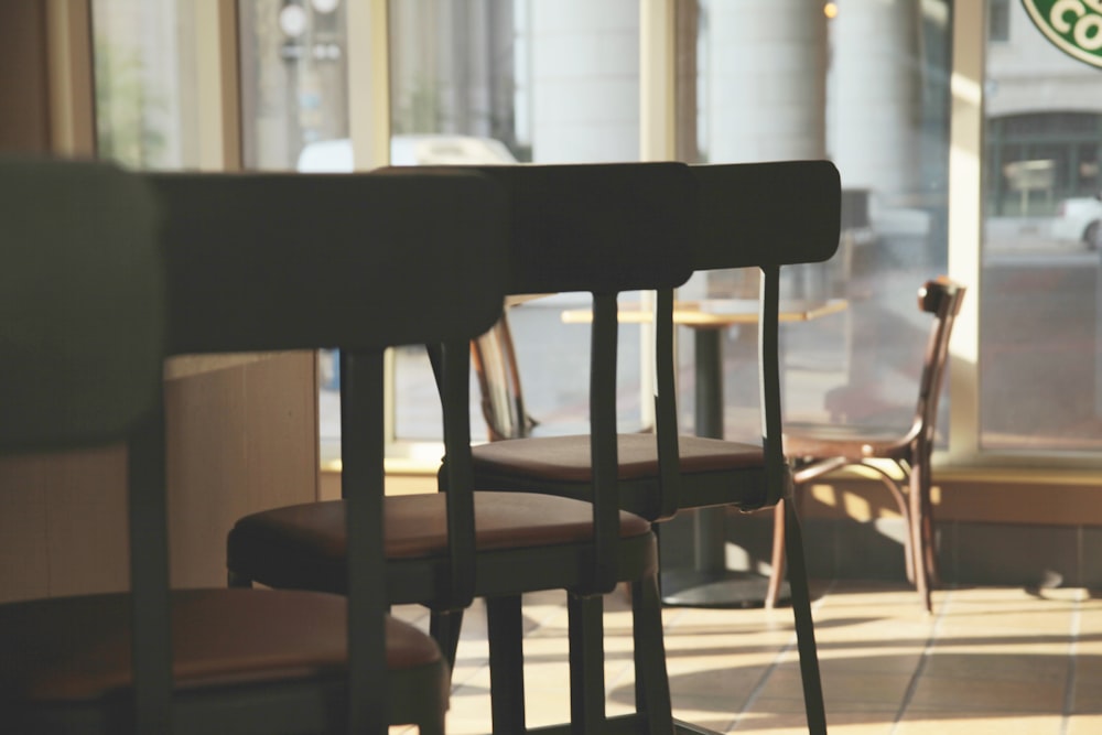 Fotografia di silhouette di sgabelli da bar grigi posizionati a lato del bancone del bar in un negozio poco illuminato