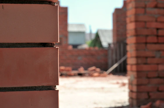 A close-up shot of skilled workers carefully laying bricks on a sunny construction site.