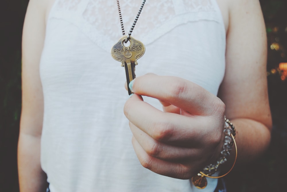 person holding gold-colored key pendant