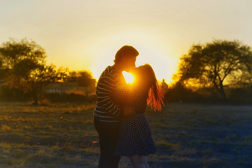 Silhouettenfotografie eines Paares, das sich in der Mitte des Feldes küsst