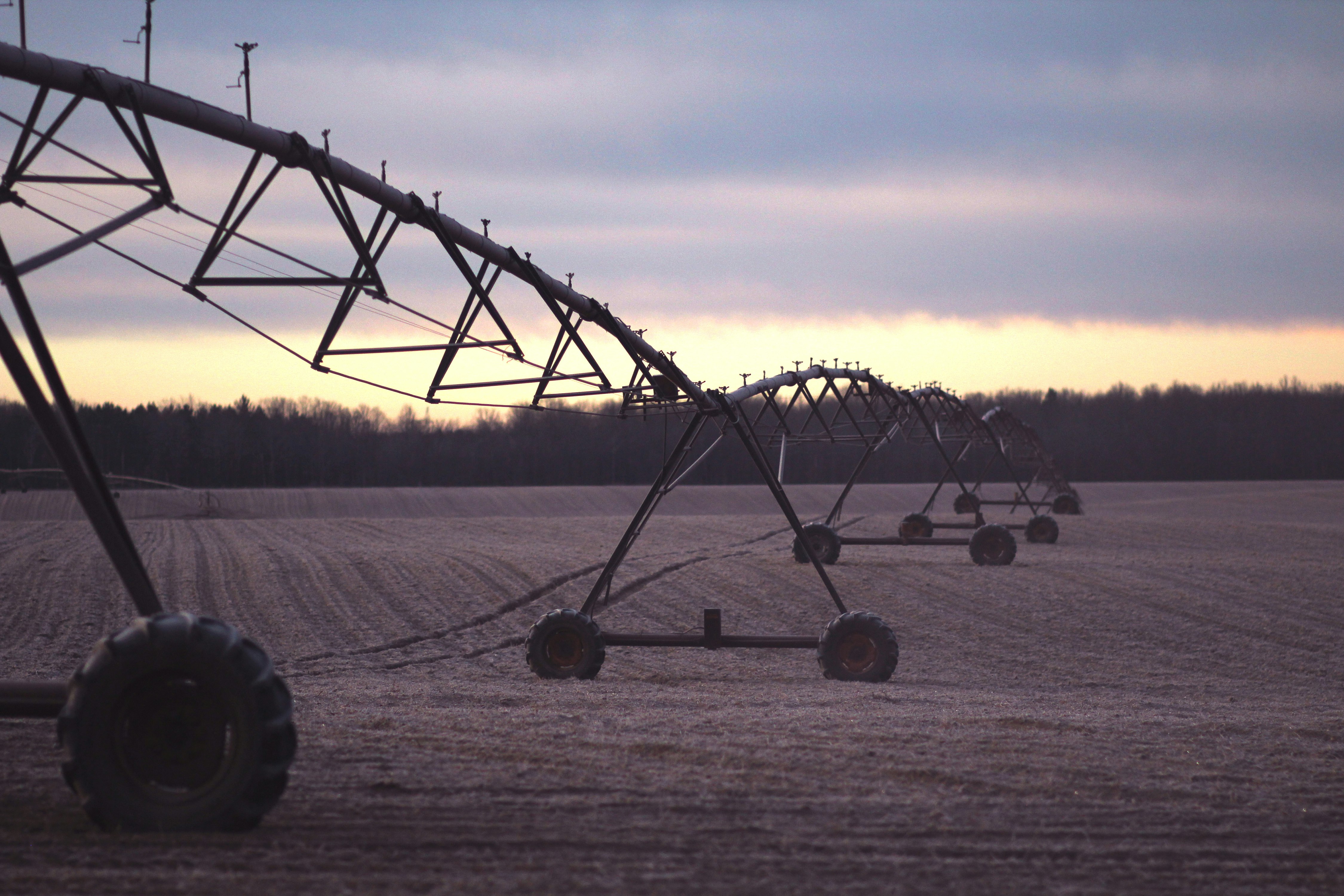 photo of black farming equipment under white clouds at daytime