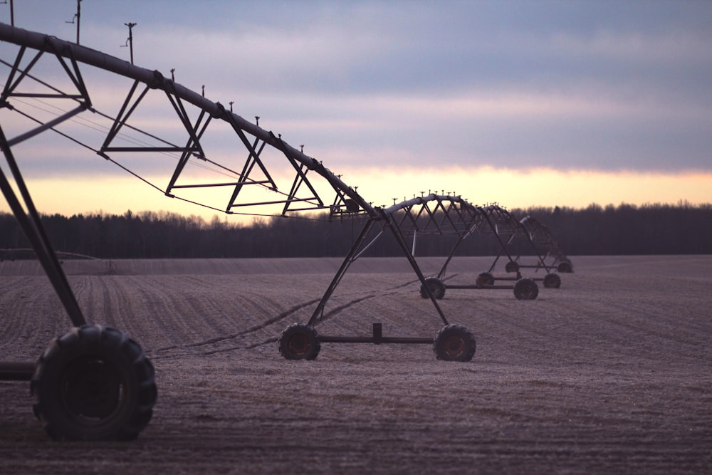 photo of black farming equipment under white clouds at daytime