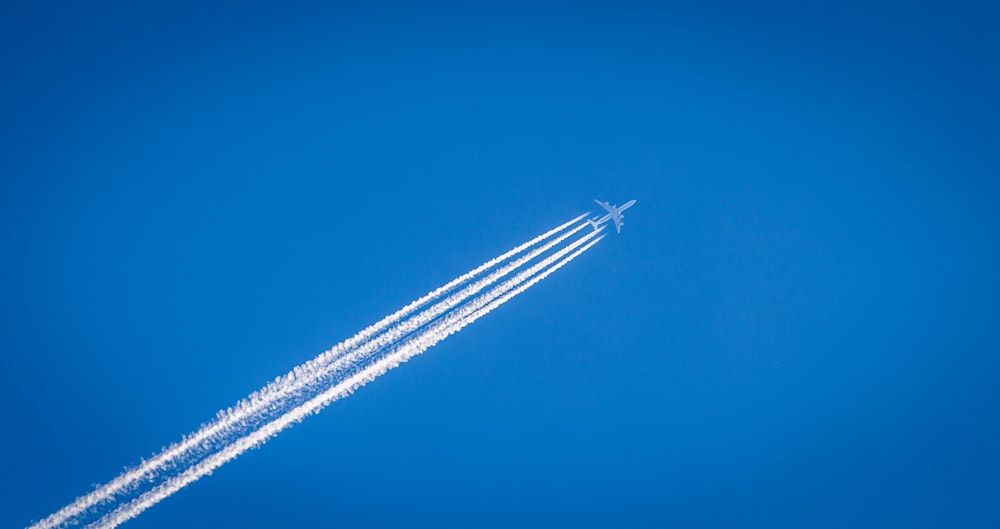 Weißes Flugzeug fliegt unter dem blauen Himmel