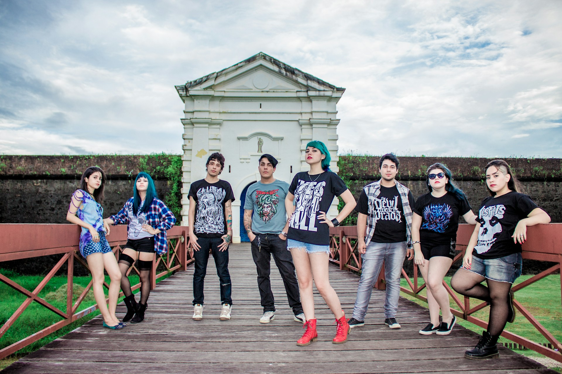 A diverse group of young adults wearing casual, stylish outfits outdoors on a sunny day.