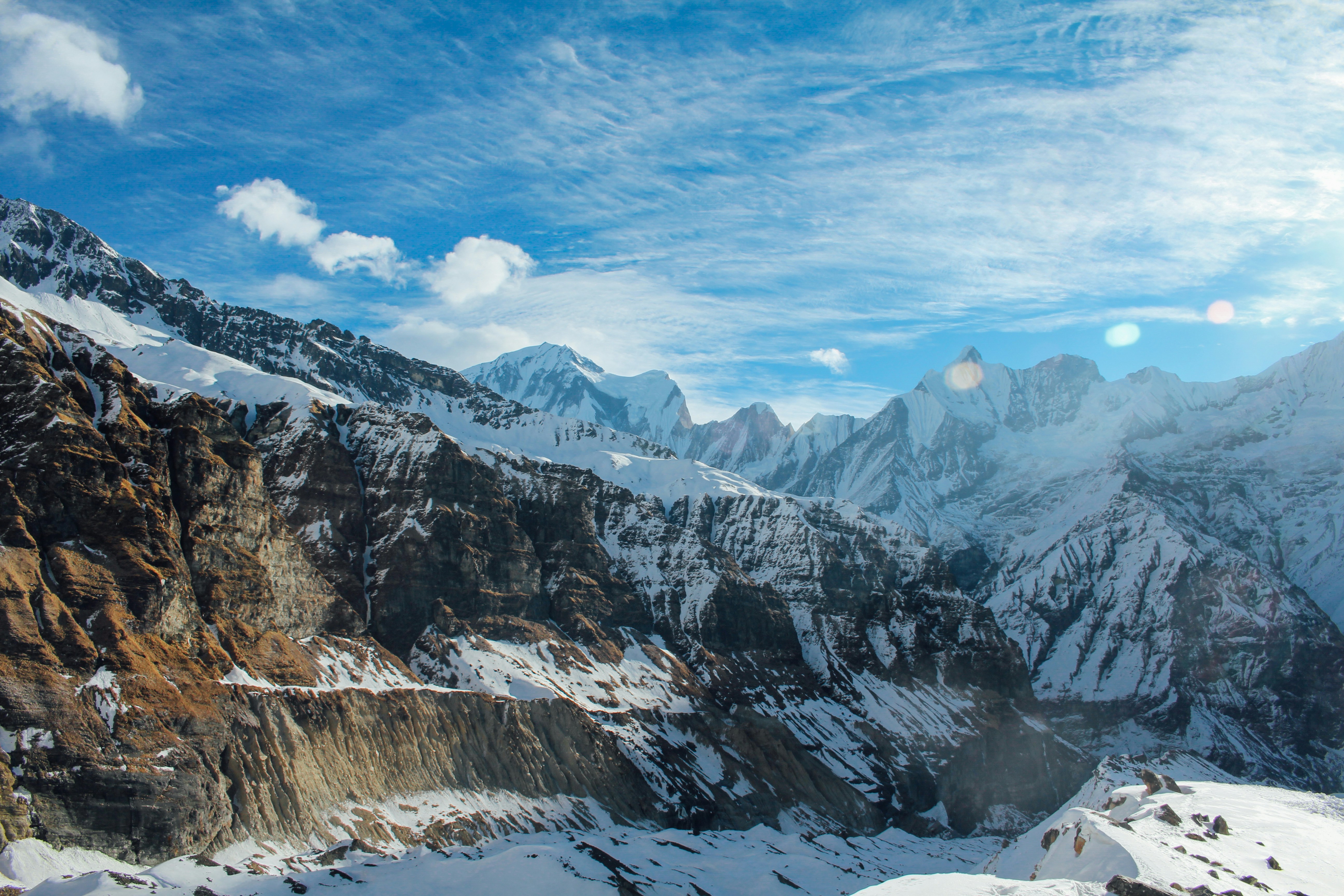 aerial photography of rock mountain covered with snow under blue sky and white clouds view, Snowy Mountains