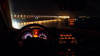 A cozy car interior with a glowing radio display tuned to an XM FM channel, evening city lights visible through the windshield.
