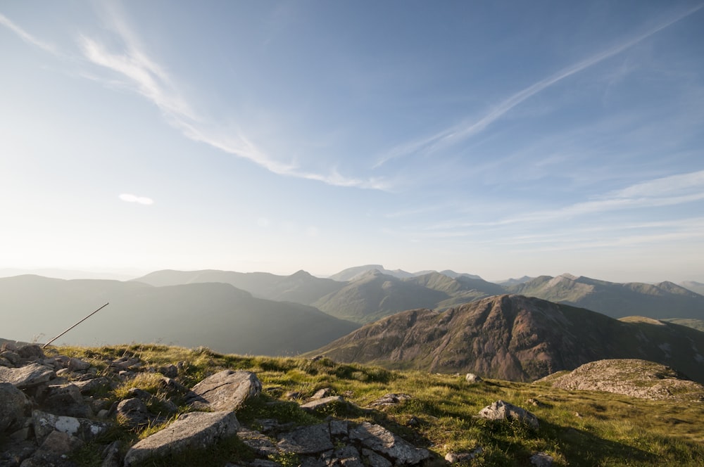 rock and grass covered field and mountains at the distance