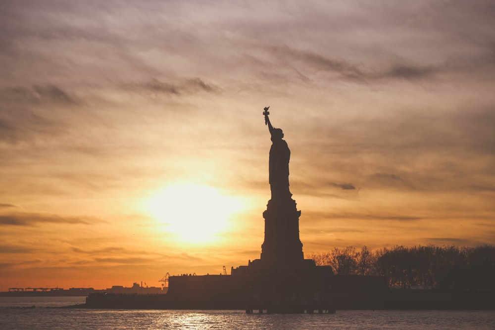 silhouette photo of Statue of Liberty during golden hour