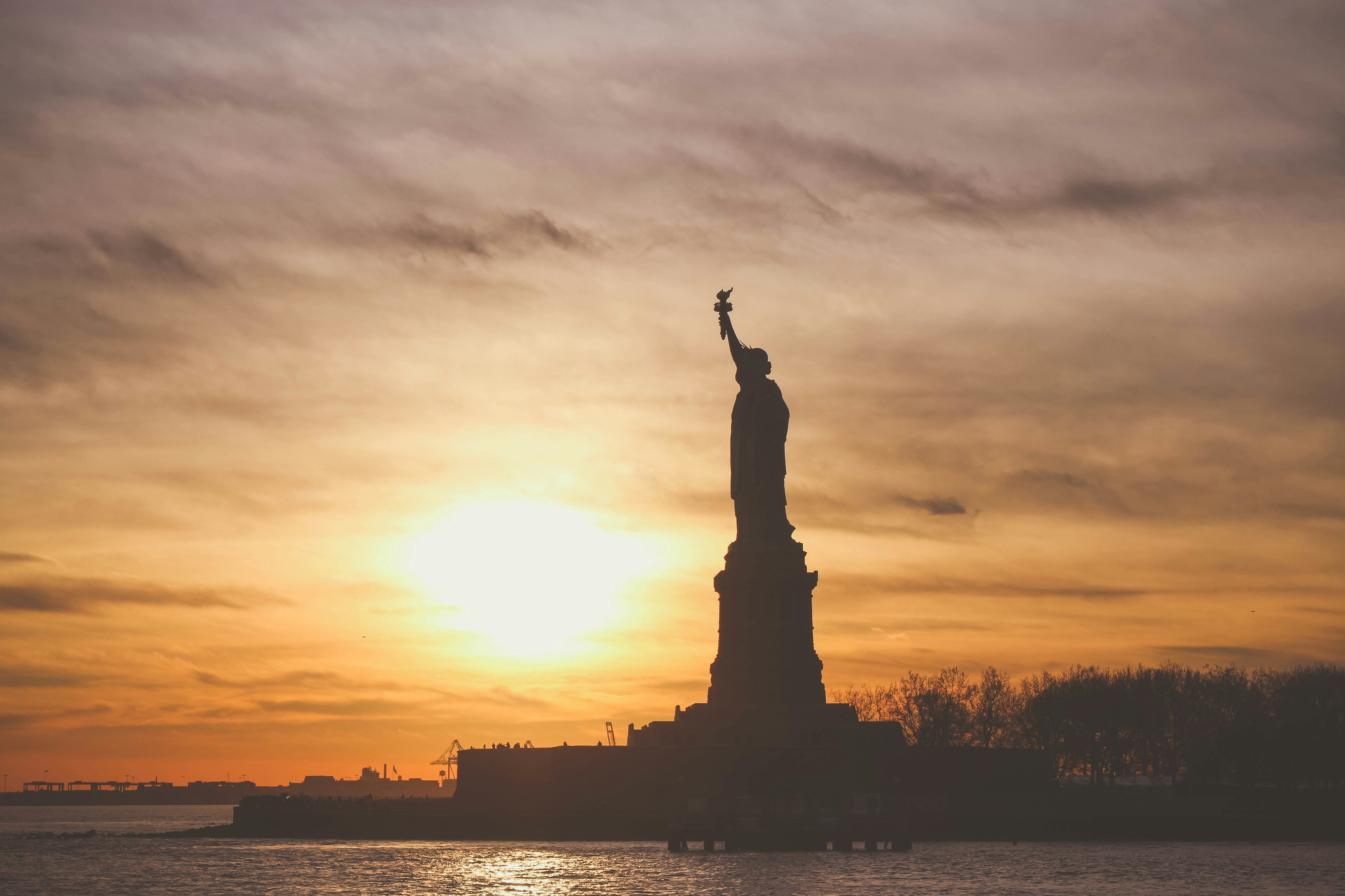 silhouette photo of Statue of Liberty during golden hour