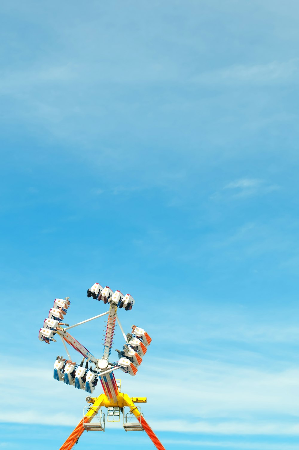 Foto einer gelben, orangefarbenen und blauen Vergnügungsparkfahrt unter strahlend blauem Himmel