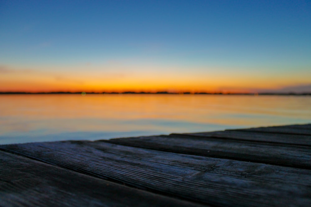 selective focus photo of brown wood planks in front of beach during golden hour