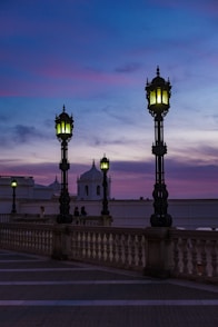 black metal lamp post near white concrete fence during sunset