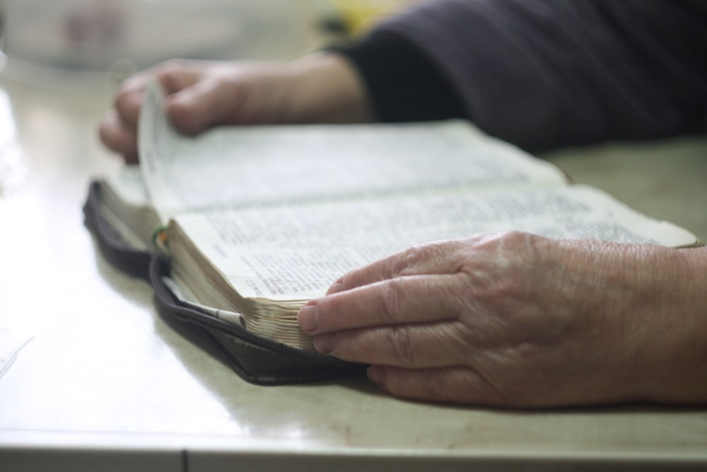 Une personne qui tourne la page d’un livre ouvert.