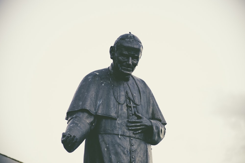 statua di Papa Giovanni Paolo in cemento nero durante il giorno