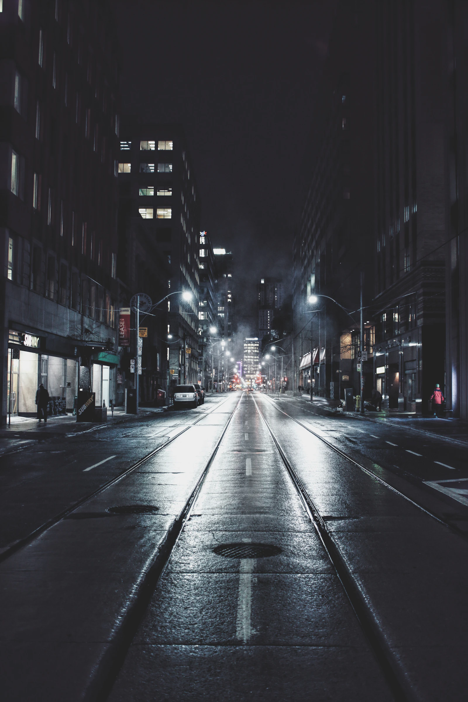 An empty city road at night lit by street lamps