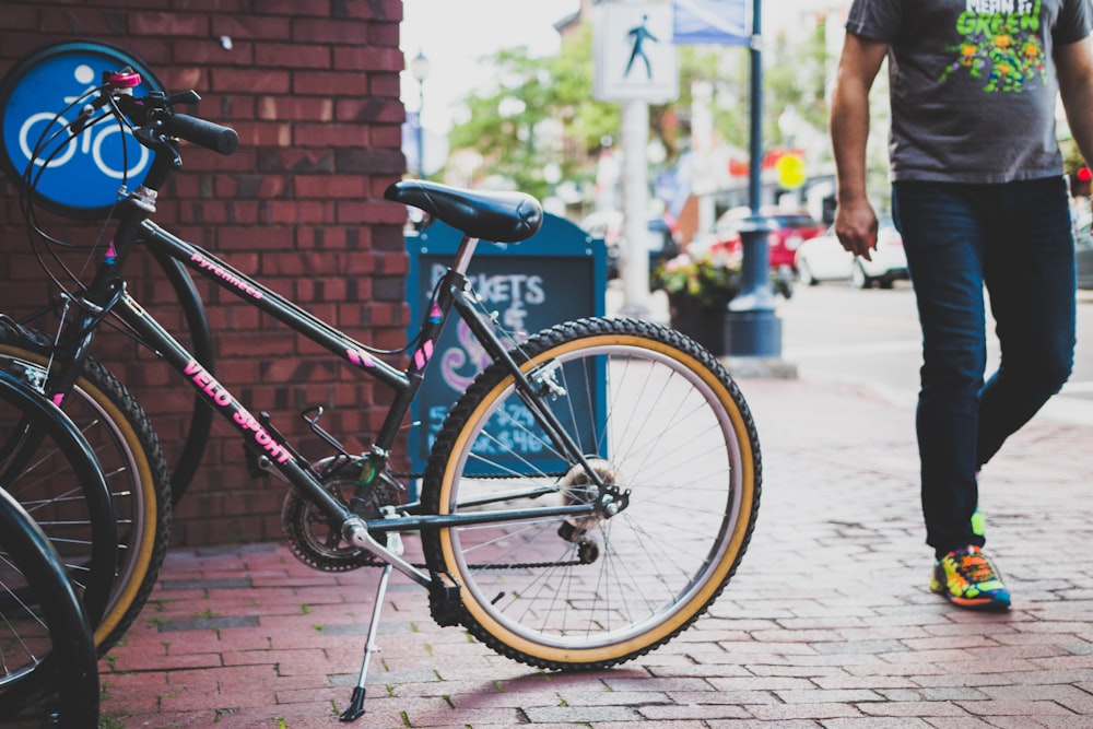 black bicycle parked beside brick wall