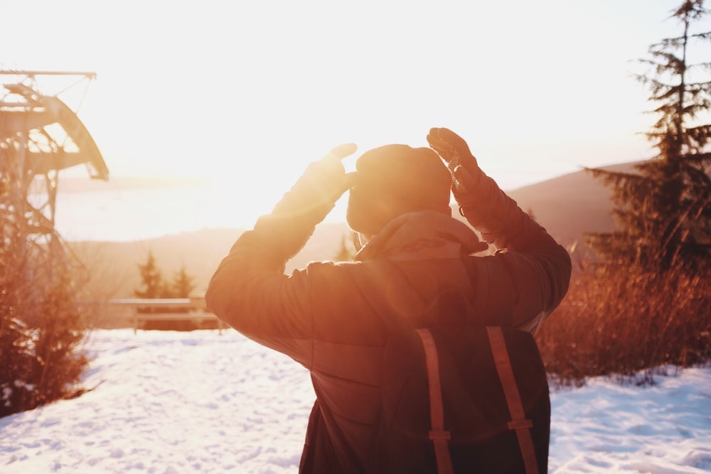 person wearing winter clothes on snow-covered hill during sunrise