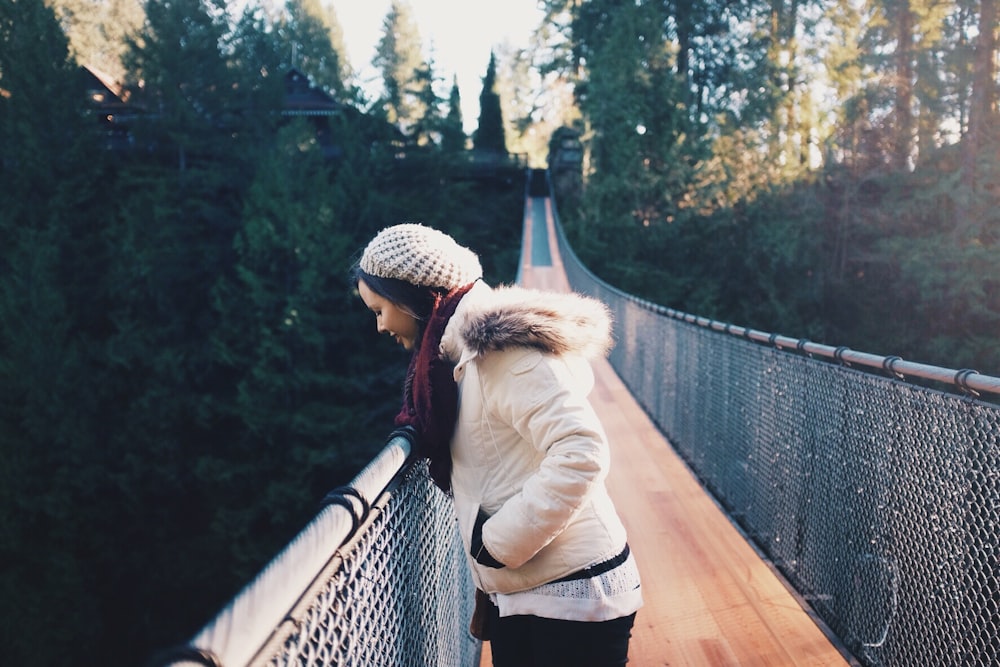 Donna in piedi sul ponte marrone mentre guarda in basso durante il giorno