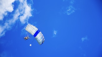 low-angle photography of person riding fan-powered chair with parachute up in sky