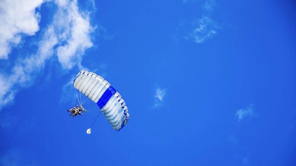 low-angle photography of person riding fan-powered chair with parachute up in sky
