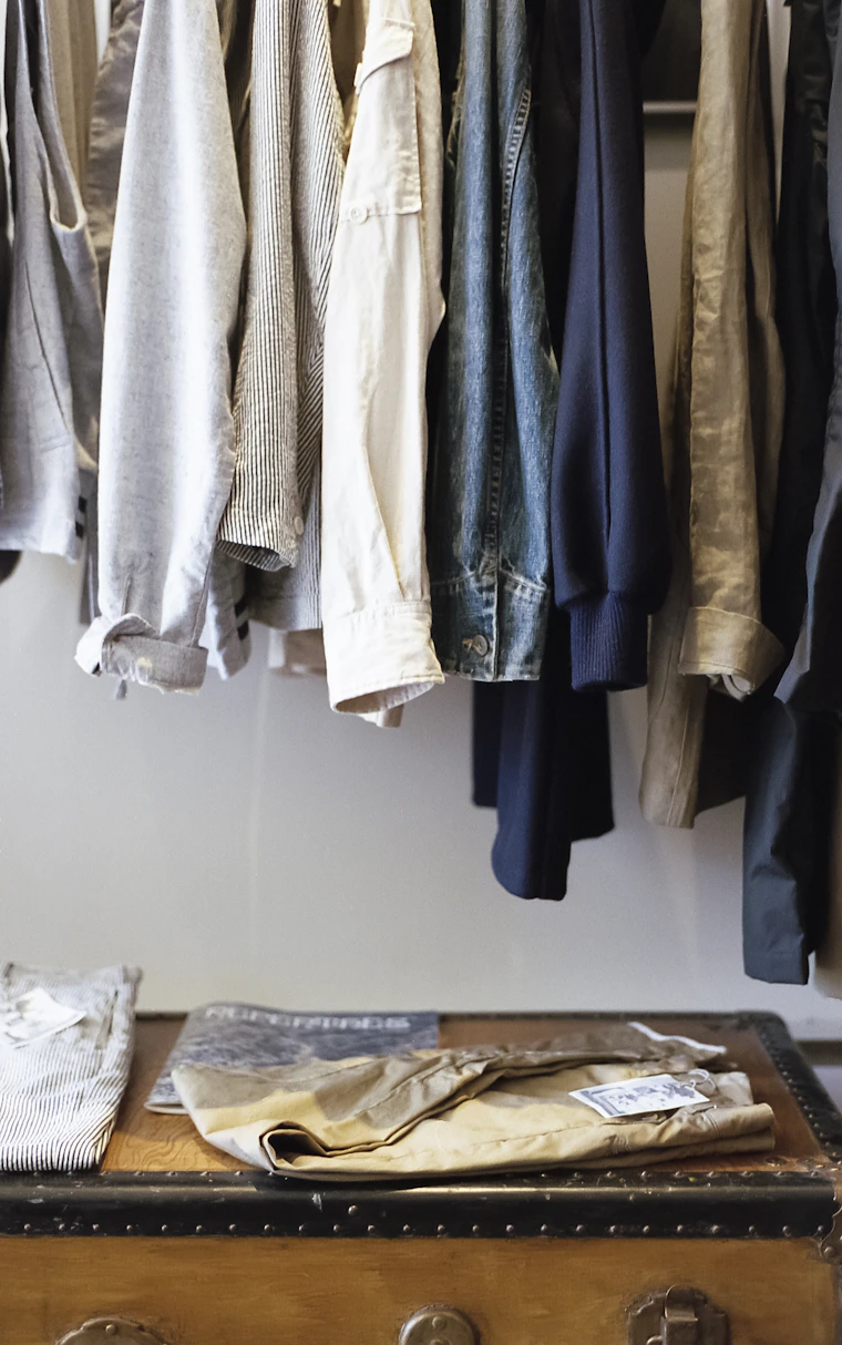 Clothing hanging on a rail protected by poly garment bags and suit covers