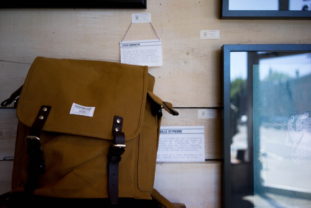 brown knapsack beside flat screen TV