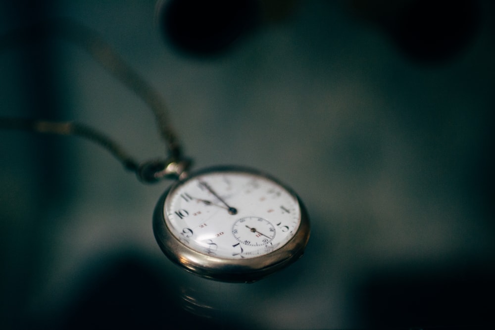 Fotografía con poca luz del reloj de bolsillo blanco