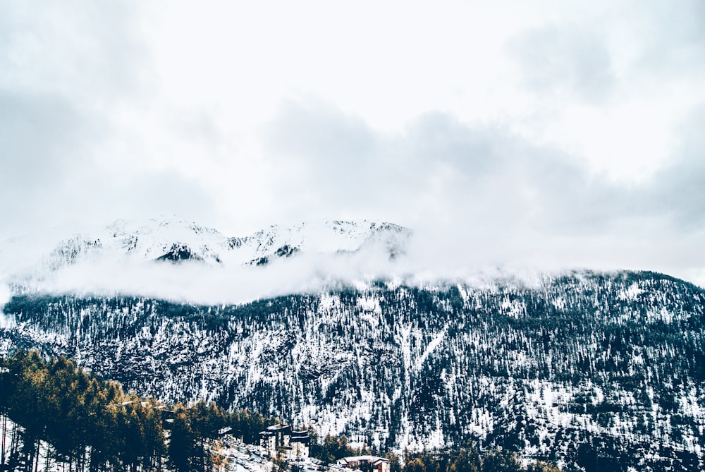 snow covered mountain under white clouds during daytime