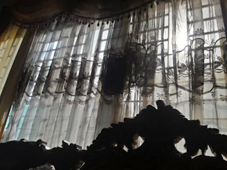 Elegant bedroom with vintage decor and soft natural light filtering through lace curtains.