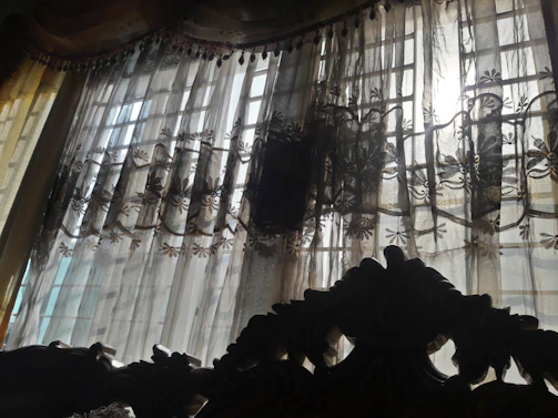 Elegant bedroom with vintage decor and soft natural light filtering through lace curtains.