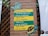 A brick wall with a wooden lattice features a colorful sign. The sign, themed with a turtle and a frog, contains ecological guidance in Portuguese text. The messages emphasize respect for nature, advising to leave no trace and to refrain from harming the environment.
