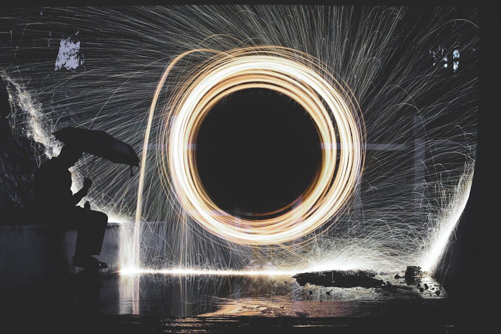 photo of person holding umbrella near steelwool during nighttime